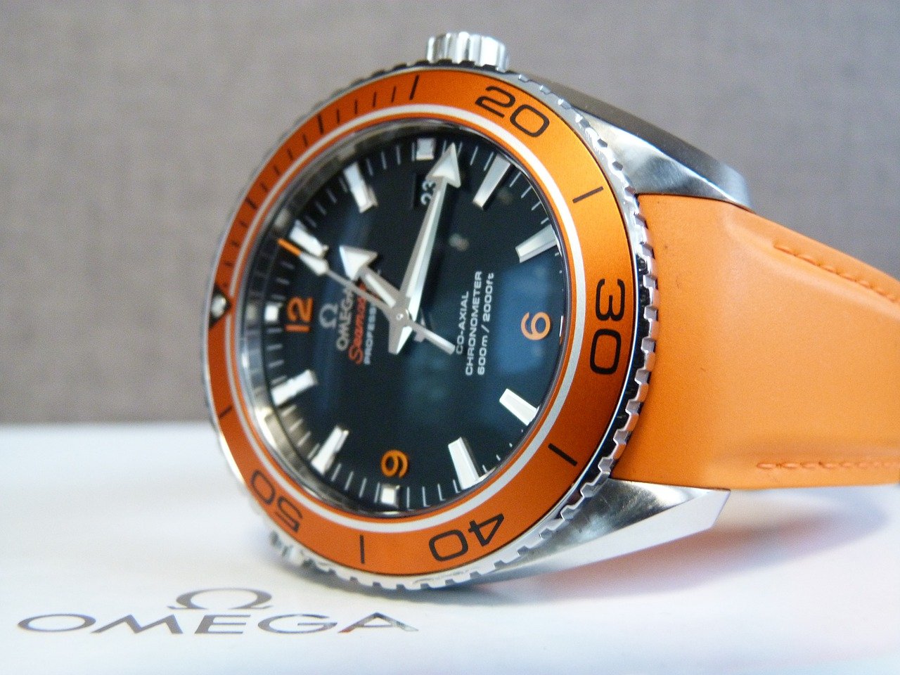 Orangene Omega Armbanduhr liegt auf der OVP